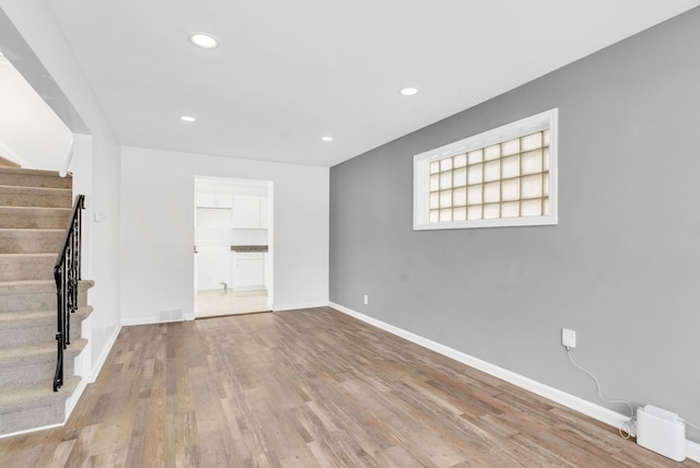 interior space with light wood-style flooring, recessed lighting, stairway, and baseboards