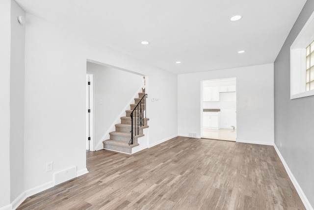 spare room featuring light wood-style floors, stairs, and recessed lighting