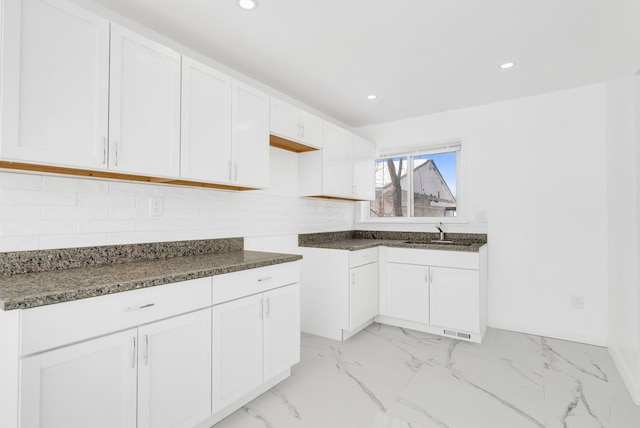 kitchen featuring marble finish floor, white cabinets, backsplash, and recessed lighting