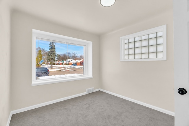 empty room featuring carpet floors, visible vents, and baseboards