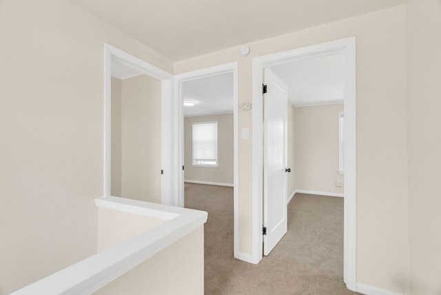 hall featuring light carpet and baseboards