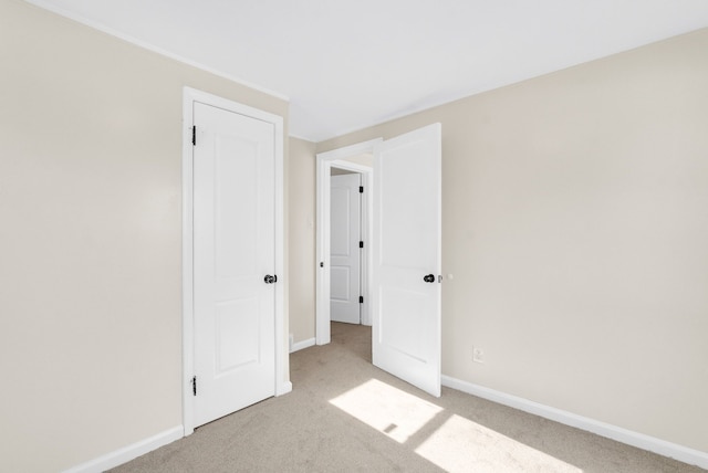 unfurnished bedroom featuring baseboards and light colored carpet