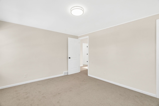 empty room featuring light carpet, visible vents, and baseboards