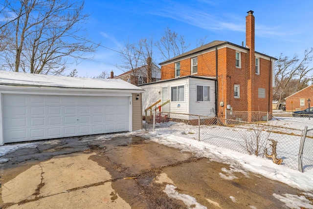 view of front of home with an outbuilding, entry steps, brick siding, fence, and a chimney