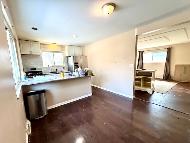 kitchen featuring tasteful backsplash, baseboards, appliances with stainless steel finishes, dark wood-style flooring, and a sink