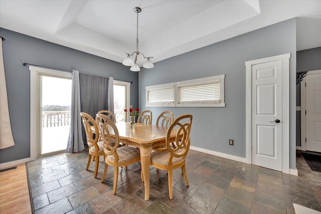 3912 Alex Ct, Oxford, MI 48371 - dining area featuring stone tile floors, a tray ceiling, baseboards, and a chandelier
