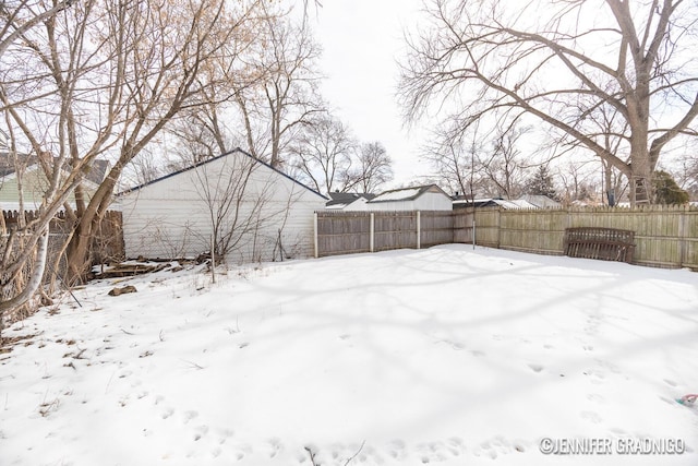 snowy yard featuring a fenced backyard