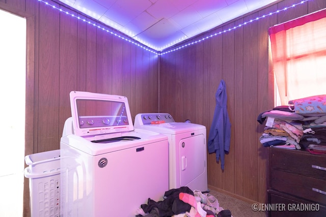 washroom with laundry area, separate washer and dryer, wood walls, and carpet flooring