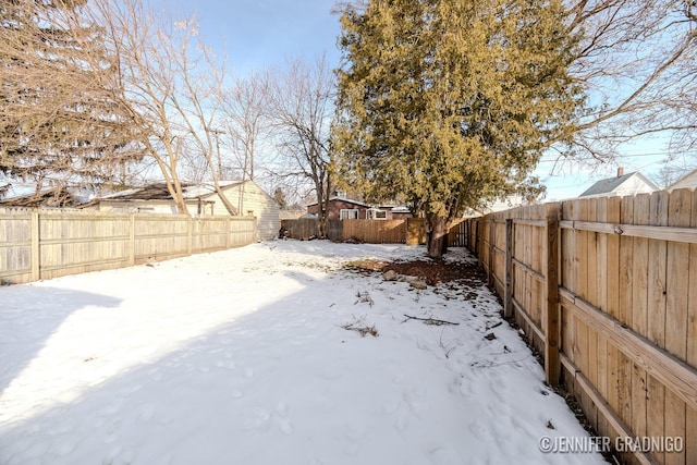 yard layered in snow with a fenced backyard