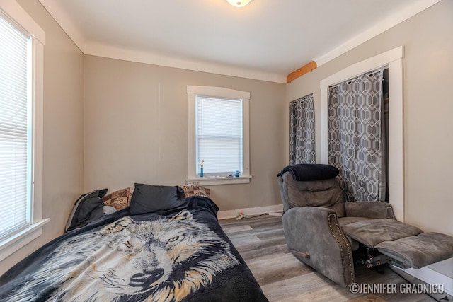 bedroom featuring baseboards, multiple windows, and light wood finished floors