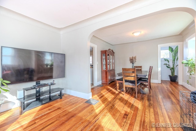 dining space with baseboards, visible vents, arched walkways, and hardwood / wood-style floors