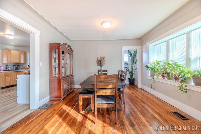 dining area featuring visible vents, baseboards, and wood finished floors