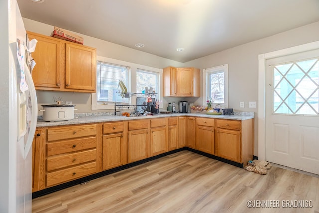 kitchen with light wood-style floors, white refrigerator with ice dispenser, and light countertops