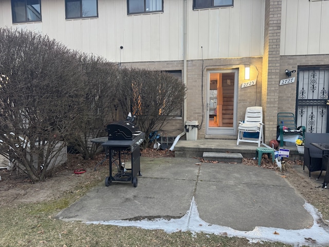 property entrance with brick siding and a patio area