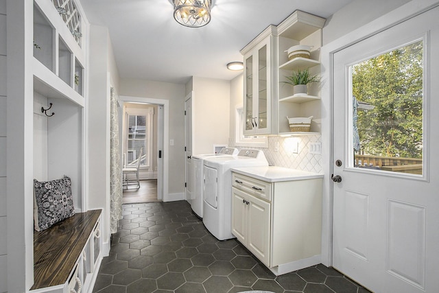 clothes washing area featuring dark tile patterned floors, independent washer and dryer, cabinet space, and baseboards