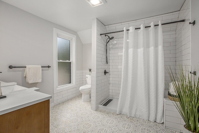 bathroom featuring toilet, vanity, visible vents, a tile shower, and tile patterned floors