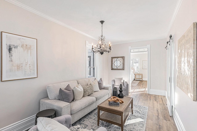 living area with light wood-style floors, a barn door, baseboards, and crown molding