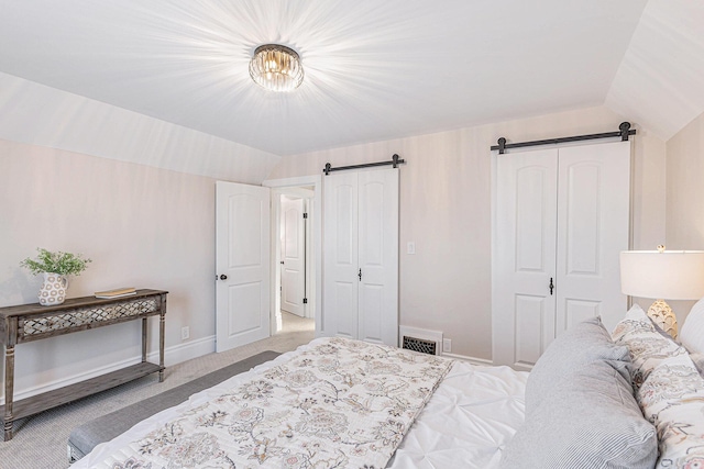 bedroom featuring carpet floors, lofted ceiling, visible vents, a barn door, and baseboards