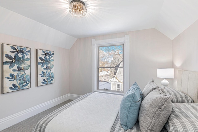 carpeted bedroom featuring vaulted ceiling and baseboards