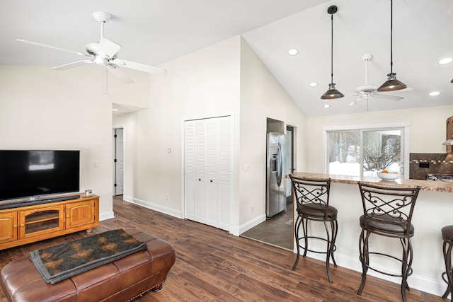 living area featuring baseboards, a ceiling fan, dark wood-style floors, high vaulted ceiling, and recessed lighting