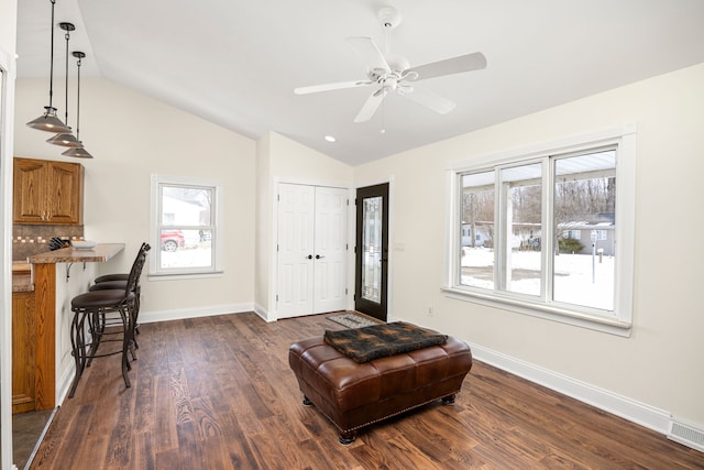 sitting room featuring lofted ceiling, ceiling fan, dark wood-type flooring, visible vents, and baseboards