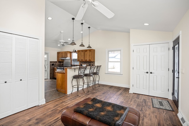 living area featuring lofted ceiling, recessed lighting, dark wood-style flooring, visible vents, and a ceiling fan