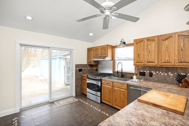 kitchen with appliances with stainless steel finishes, brown cabinets, vaulted ceiling, and under cabinet range hood