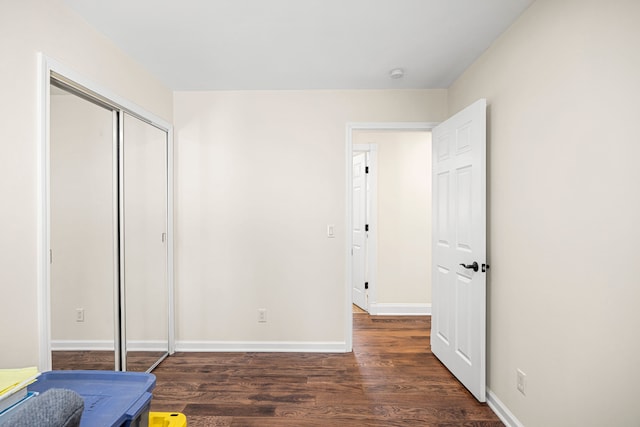 unfurnished bedroom featuring a closet, baseboards, and wood finished floors