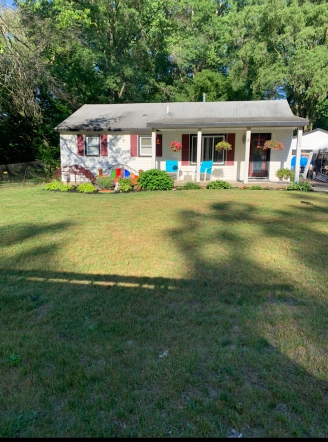 ranch-style home featuring covered porch and a front yard