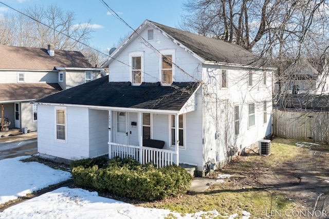 traditional-style house featuring a porch, a shingled roof, cooling unit, and fence