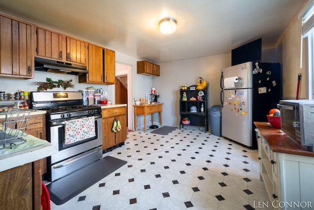 kitchen with brown cabinets, light floors, stainless steel appliances, light countertops, and under cabinet range hood