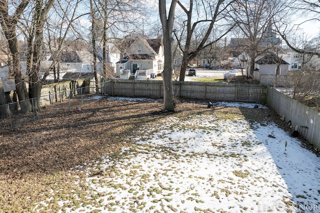 snowy yard featuring a fenced backyard and a residential view