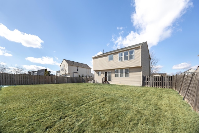 rear view of property featuring a fenced backyard and a lawn