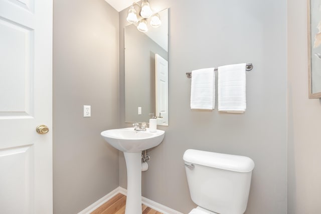 bathroom featuring toilet, an inviting chandelier, baseboards, and wood finished floors