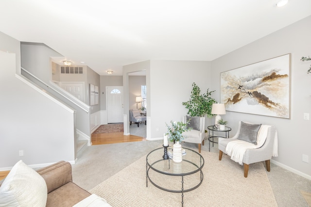 sitting room with visible vents, light carpet, baseboards, and stairs