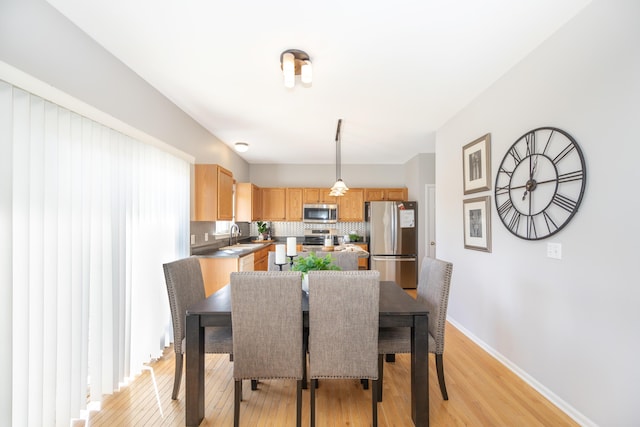 dining area with light wood-type flooring and baseboards