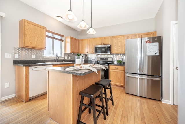 kitchen with stainless steel appliances, backsplash, dark countertops, and a kitchen island