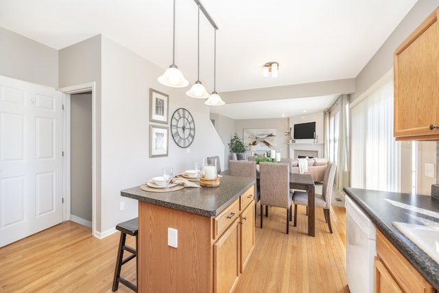 kitchen featuring dark countertops, open floor plan, a center island, white dishwasher, and pendant lighting