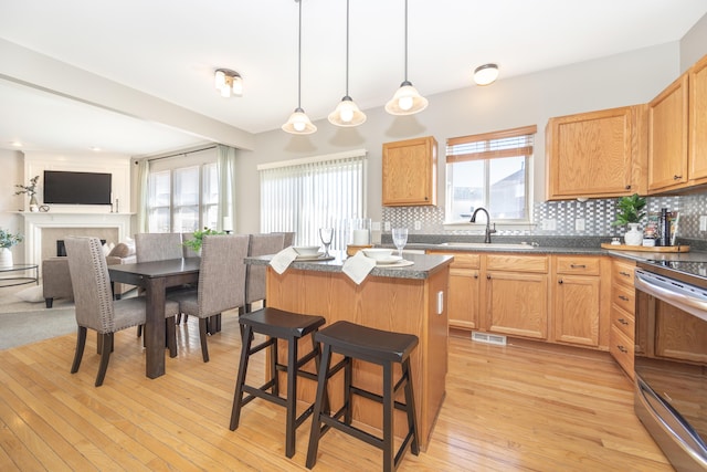 kitchen featuring a center island, tasteful backsplash, dark countertops, stainless steel range with electric stovetop, and a kitchen breakfast bar