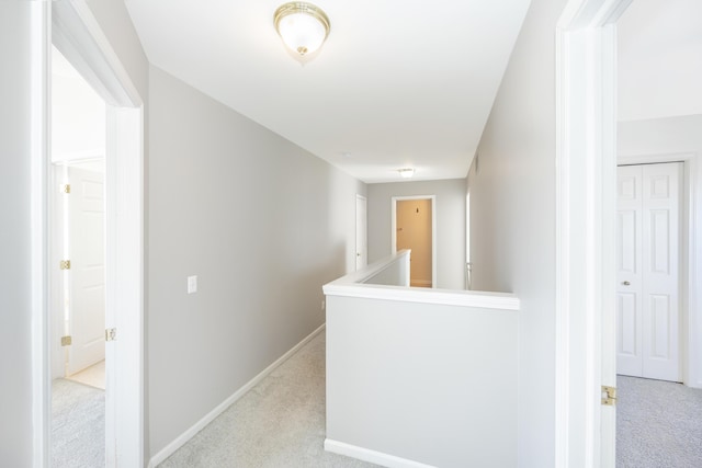 hall with baseboards, light carpet, and an upstairs landing