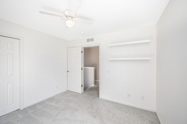 unfurnished bedroom featuring baseboards, visible vents, light colored carpet, ceiling fan, and a closet