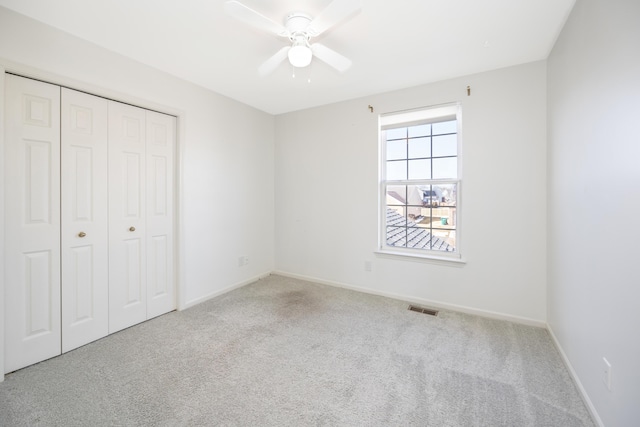 unfurnished bedroom featuring baseboards, visible vents, a closet, and light colored carpet