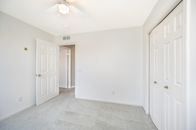 unfurnished bedroom with a closet, light colored carpet, visible vents, and baseboards