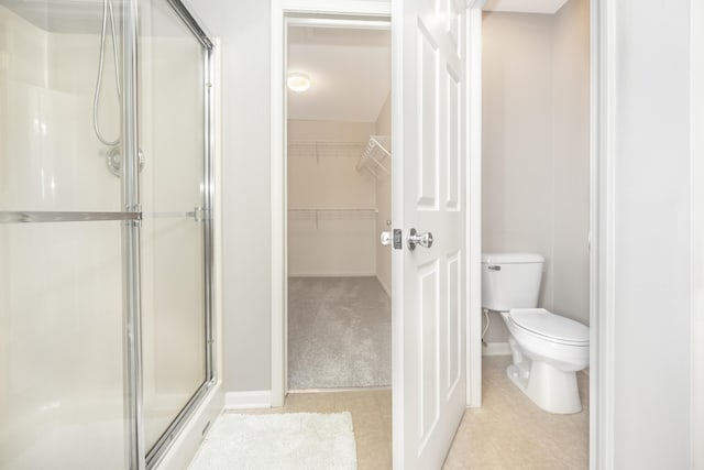 bathroom with a stall shower, a walk in closet, and toilet