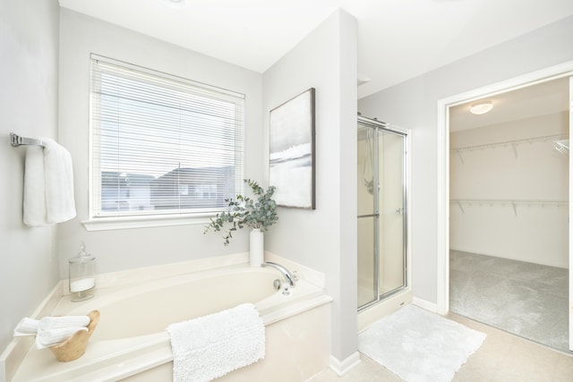 bathroom featuring a garden tub, a shower stall, and baseboards