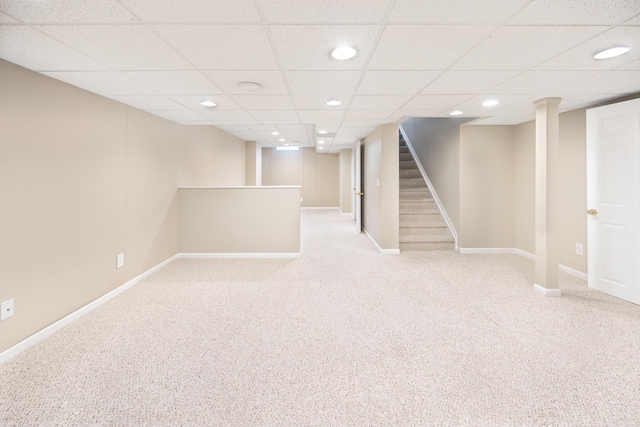 finished basement with a drop ceiling, recessed lighting, light colored carpet, baseboards, and stairway