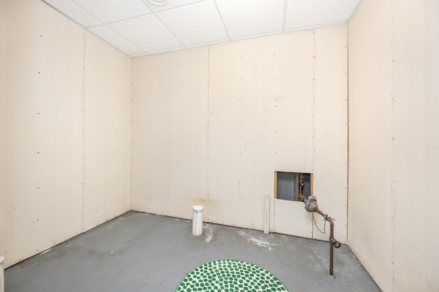 spare room with a paneled ceiling and unfinished concrete floors