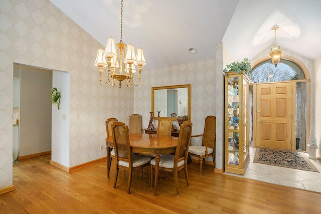 dining area with a chandelier, light wood-style flooring, baseboards, and wallpapered walls