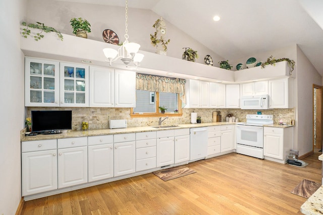 kitchen with light wood finished floors, lofted ceiling, white cabinets, a sink, and white appliances