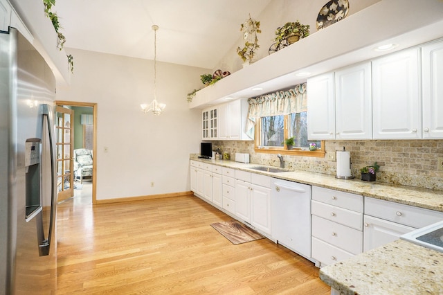 kitchen featuring light wood-style flooring, vaulted ceiling, white dishwasher, a sink, and stainless steel fridge